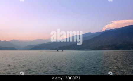 Phewa See mit Annapurna Bereich in Pokhara, Nepal. Menschen genießen friedliche Zeit auf einem Boot bei Sonnenuntergang. Stockfoto