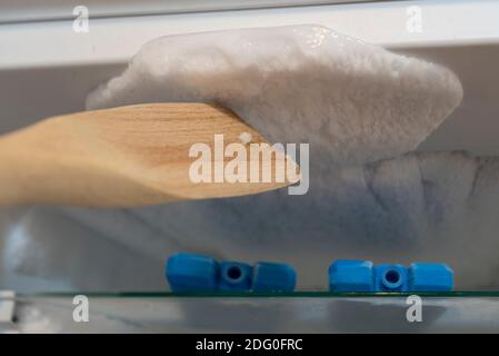 Magdeburg, Deutschland. Dezember 2020. Ein Mann benutzt einen Holzlöffel, um die Eisschicht in einem Gefrierschrank abzukratzen. Quelle: Stephan Schulz/dpa-Zentralbild/ZB/dpa/Alamy Live News Stockfoto