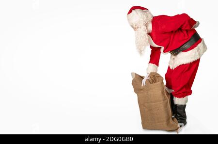 Der weihnachtsmann hat Rückenschmerzen und hält ein Geschenk Tasche isoliert vor weißem Hintergrund Stockfoto