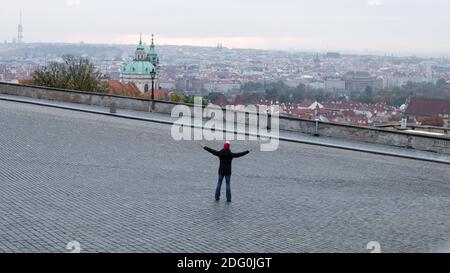 PRAG, TSCHECHISCHE REPUBLIK - 19. OKTOBER 2020: Leerer Hradcanske Namesti Platz an einem kalten Herbstmorgen, mit einer einsamen Person, die die Hände ausstreckt Stockfoto