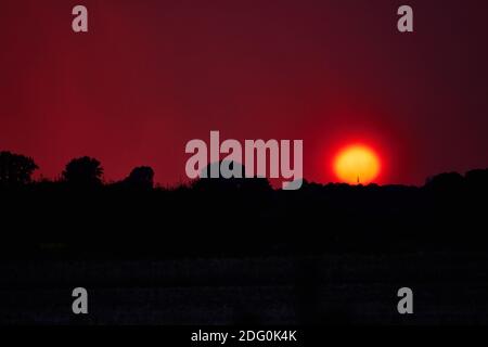 Erstaunlicher apokalyptischer Sonnenuntergang vor einem rot-violetten Himmel Stockfoto