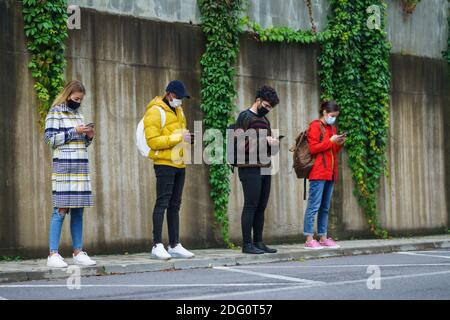 Junge Menschen mit Smartphone im Freien in der Stadt. Coronavirus und sicheres Entfernungskonzept. Stockfoto