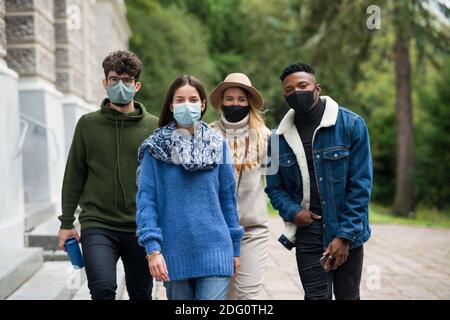 Gruppe von jungen Menschen mit Gesichtsmaske im Freien in der Stadt, zu Fuß. Coronavirus-Konzept. Stockfoto