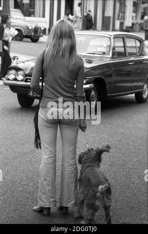 Eine junge Frau mit Hund überquert die Straße. London, England, 1971 Stockfoto