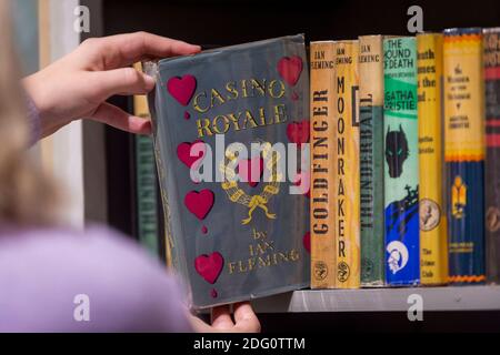 London, Großbritannien. Dezember 2020. Ein Mitarbeiter posiert mit einer ersten Ausgabe von "Casino Royale" von Ian Fleming (£12,500). Start des neuen Shapero Emporium in der New Bond Street. Das Emporium ist ein Zusammenkommen von 6 renommierten Kunsthändlern, darunter Shapero Modern, Shapero Rare Books, Lennox Cato, Kent Antiques und mehr, mit Werken von Raphael, Andy Warhol, schönen islamischen und indischen höfischen Objekten und Majolika. Kredit: Stephen Chung / Alamy Live Nachrichten Stockfoto