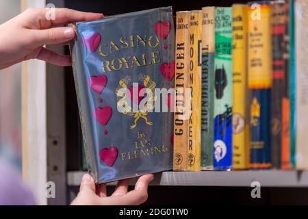 London, Großbritannien. Dezember 2020. Ein Mitarbeiter posiert mit einer ersten Ausgabe von "Casino Royale" von Ian Fleming (£12,500). Start des neuen Shapero Emporium in der New Bond Street. Das Emporium ist ein Zusammenkommen von 6 renommierten Kunsthändlern, darunter Shapero Modern, Shapero Rare Books, Lennox Cato, Kent Antiques und mehr, mit Werken von Raphael, Andy Warhol, schönen islamischen und indischen höfischen Objekten und Majolika. Kredit: Stephen Chung / Alamy Live Nachrichten Stockfoto