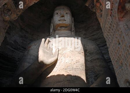 Yungang Grotten in der Nähe von Datong in der Provinz Shanxi, China. Große alte Statue von Buddha in einer Höhle bei Yungang mit der rechten Hand angehoben. Stockfoto