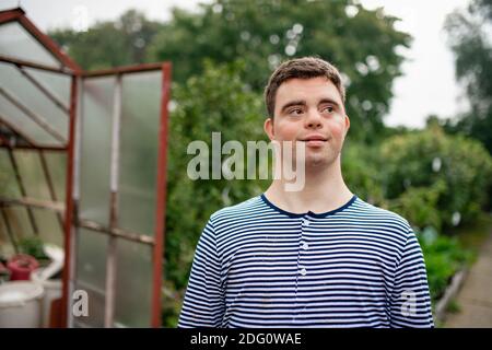 Down-Syndrom erwachsenen Mann zu Fuß im Freien im Gemüsegarten. Stockfoto