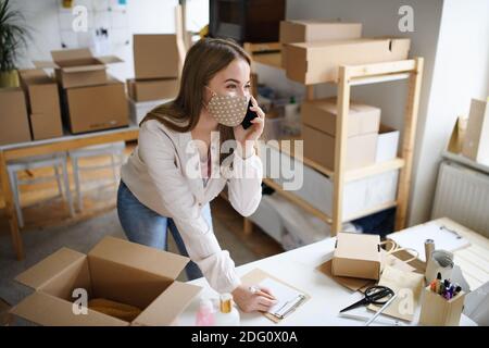 Junge Frau dropshipper mit Smartphone zu Hause arbeiten, Coronavirus Konzept. Stockfoto