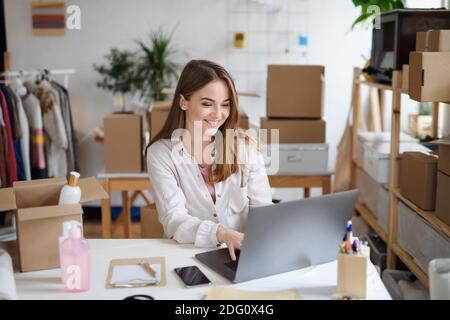 Junge Frau Dropshipper mit Laptop zu Hause arbeiten, Coronavirus Konzept. Stockfoto