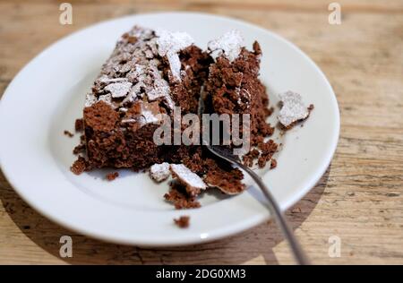 Reicher Schokoladenkuchen auf weißem Teller mit Gabel Stockfoto