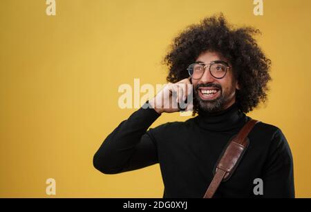 Porträt eines reifen Mannes mit Smartphone in einem Studio auf gelbem Hintergrund. Stockfoto