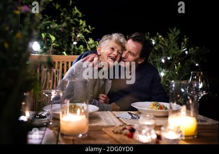 Ein glückliches Seniorenpaar, das abends auf der Terrasse zu Abend gegessen hat. Stockfoto