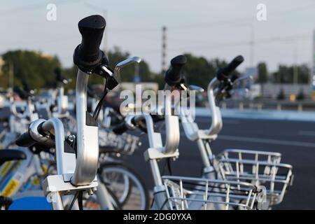 Fahrradverleih. Viele Fahrräder am Parkplatz. Nahaufnahme des Lenkers. Moderner Nahverkehr. Stockfoto