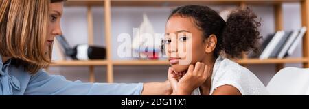 Psychologe berühren Schulter des verärgert afroamerikanischen Mädchen Blick auf Kamera während der Beratung auf verschwommenem Hintergrund, Banner Stockfoto