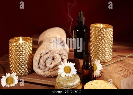 Wunderschöne Spa-Komposition. Aromatherapie mit Kräuteröl, Naturseife und Goldkerzen. Entspannungsfarbe und wärmende Handtücher auf Holzhintergrund Stockfoto