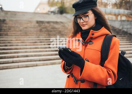 Junge Frau in Mantel und Hut nutzt Handy im Freien Im Herbst Stockfoto