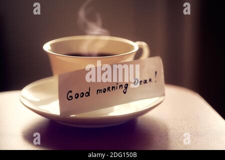 Weiße Keramik Tasse Tee oder Kaffee mit schönen Buchstaben "Guten Morgen lieber" auf Küche Holztisch. Schönes Foto mit Frühstück. Stockfoto