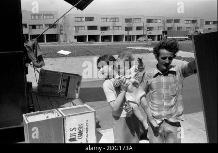 Familie zieht in ein neues Haus auf einem neuen Grundstück 1970. Vater und älteste Tochter, die ihre kleine Schwester trägt. Packkisten, alte Teeküsten, die vom Umzugswagen kommen. 1977 Milton Keynes Buckinghamshire. UK HOMER SYKES Stockfoto