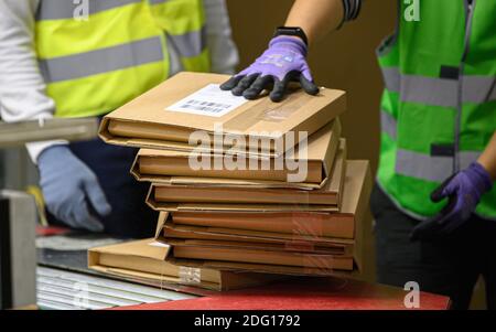 Ottendorf Okrilla, Deutschland. Dezember 2020. Die Pakete werden von den Mitarbeitern im DHL Paketcenter auf ein Förderband verladen. Im Vorfeld der Weihnachtszeit nimmt das Paketvolumen deutlich zu. (Aufnahme mit langer Verschlusszeit) Quelle: Robert Michael/dpa-Zentralbild/dpa/Alamy Live News Stockfoto