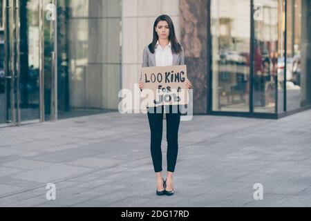 In voller Länge Foto von deprimiert traurig junge hübsche Geschäftsfrau Halten Karte aussehen Job tragen Jacke im Freien Stockfoto