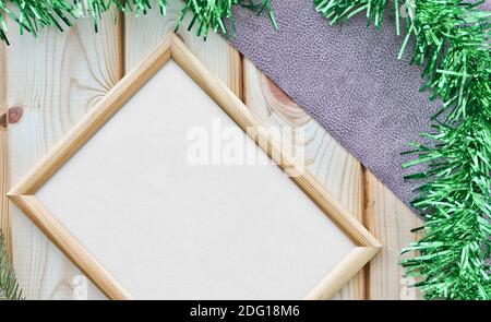 Leerer beiger Holzrahmen mit antikem Papier auf der Oberfläche von Holzlatten und einem Fichtenzweig. Platz kopieren, Draufsicht. Weihnachtsthema. Stockfoto