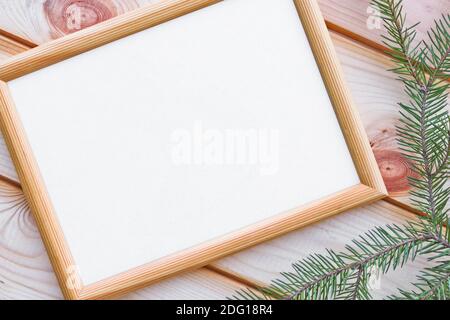 Leerer beiger Holzrahmen mit antikem Papier auf der Oberfläche von Holzlatten und einem Fichtenzweig. Platz kopieren, Draufsicht. Weihnachtsthema. Stockfoto