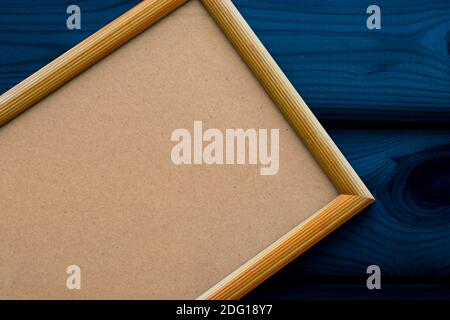 Leerer beiger Holzrahmen mit antikem Papier auf der dunkelblauen Oberfläche der Holzlatten. Platz kopieren, Draufsicht. Weihnachtsthema. Stockfoto