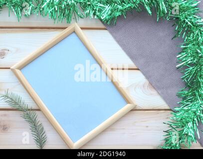 Leerer beiger Holzrahmen mit antikem Papier auf der Oberfläche von Holzlatten und einem Fichtenzweig. Platz kopieren, Draufsicht. Weihnachtsthema. Stockfoto