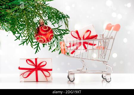 Shopping zum neuen Jahr. Mini-Wagen mit Geschenkboxen auf weißem Hintergrund. Stockfoto