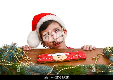 Ein Junge von 10-13 Jahren in einem roten Weihnachtshut wartet auf das neue Jahr oder Weihnachten. Junge rollt die Augen. Warten auf Weihnachten Nacht, Urlaub Stockfoto