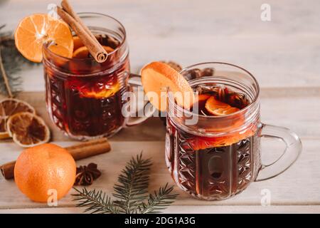 Heißer Glühwein mit Gewürzen in Glas Tasse auf Holz Hintergrund. Weihnachtliches Getränk. Stockfoto