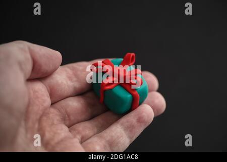 Mann, der eine Geschenkbox aus Plastilin in der Hand hält. Geringe Schärfentiefe. Stockfoto