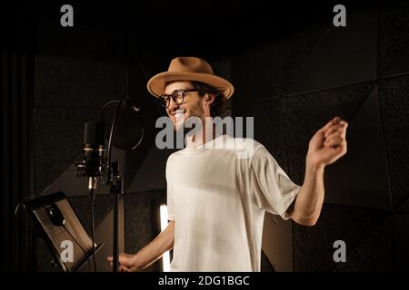 Schöner stilvoller Musiker im Hut glücklich tanzen Aufnahme neuer Song Im Tonstudio Stockfoto