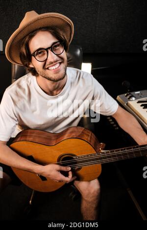 Porträt von attraktiven fröhlichen Mann glücklich spielen auf einer Gitarre Aufnahme neuer Songs im Musikstudio Stockfoto