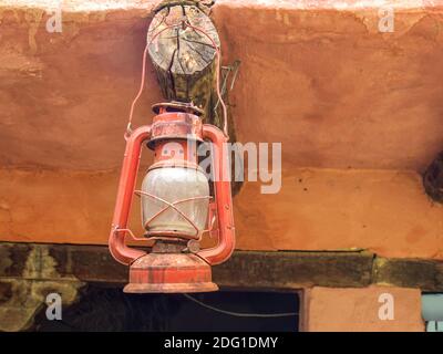 Antike Öllampe der Bergleute, die an einem Holzbalken an einem Haus in der klonischen Stadt Villa de Leyva in den zentralen Andenbergen Kolumbiens hängt. Stockfoto