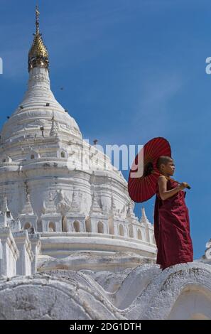 Junge Novizin buddhistischer Mönch holding Sonnenschirm am Myatheindan Pagode (auch als Hsinbyume Pagode bekannt), Mingun, Myanmar (Burma), Asien im Februar Stockfoto