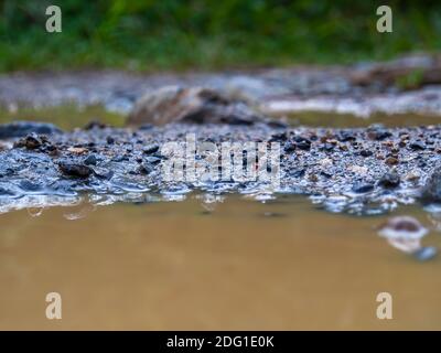 Makrofotografie des Kieses am Rande einer Pfütze auf einer Landstraße in der Nähe der Stadt Gachantiva, in den zentralen Andenbergen Kolumbiens. Stockfoto