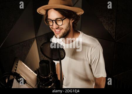 Schöner lächelnder männlicher Sänger, der gerne neue Lieder für Musik aufzeichnete Album im modernen Studio