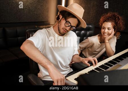 Junge stilvolle Sänger schaffen Musik in modernen Tonstudio. Attraktive Musiker arbeiten im Aufnahmestudio Stockfoto