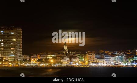 Nachtaufnahme mit Vollmond hinter den Wolken, Stadt Palamos an der spanischen Costa Brava, Katalonien Stockfoto