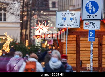 Leipzig, Deutschland. Dezember 2020. Passanten gehen durch die Fußgängerzone in der Grimmaische Straße in der Leipziger Innenstadt vor einem Schild mit der Aufschrift "Alle für alle - 6:00 bis 24:00", das darauf hinweist, dass Masken obligatorisch sind. Die Coronapandemie breitet sich derzeit besonders schnell in Sachsen aus. Daher sind jetzt strengere Maßnahmen in Kraft, einschließlich Ausstiegsbeschränkungen. Alle Weihnachtsmärkte und die traditionellen Bergparaden im Erzgebirge sind abgesagt. (Aufnahme mit längerer Belichtungszeit) Credit: Jan Woitas/dpa-Zentralbild/dpa/Alamy Live News Stockfoto