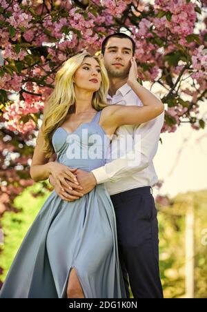 Angenehme Zeit verbringen. Paar in der Liebe Kuss und Umarmung. Frühlingsblumenblüte. Mann und Frau im Park mit rosa blühenden Kirsche. Schönheit und Mode. Süße Flitterwochen. Romantisches Paar unter Sakura Baum. Stockfoto