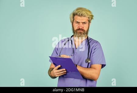 Er trägt ein Stethoskop. Krankenschwester, die Bindemittel hält und Stethoskop trägt. Reifer bärtiger männlicher Arzt mit einem Ordner in Uniform stehend. Porträt einer ernsthaften Krankenschwester mit einer Mappe. Stockfoto