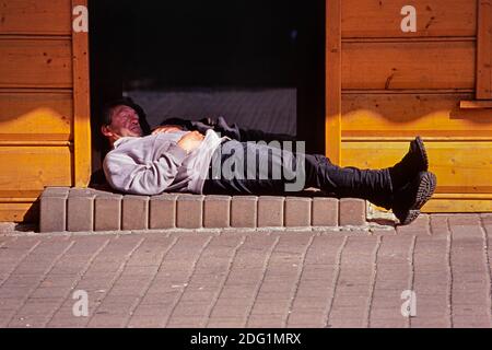 Ein betrunkener Mann, der in der Tür eines Wodka-Ladens schläft. Zakopane. Polen. Stockfoto