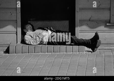 Ein betrunkener Mann, der in der Tür eines Wodka-Ladens schläft. Zakopane. Polen. Stockfoto