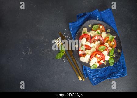 Caprese Salat zum Valentinstag Abendessen, mit Tomaten, Käse in Form von Herzen, Basilikum. Valentine day Menü Konzept Draufsicht Kopieplatz Stockfoto