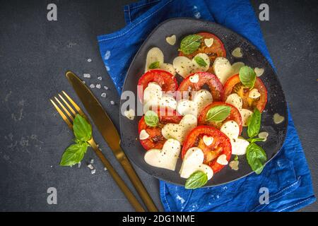 Caprese Salat zum Valentinstag Abendessen, mit Tomaten, Käse in Form von Herzen, Basilikum. Valentine day Menü Konzept Draufsicht Kopieplatz Stockfoto