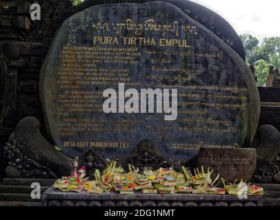 Opfergaben, die vor balinesischem Text auf geschnitztem Stein im Pura Tirtha Empul, Heiliger Frühlingstempel, in der Nähe von Ubud, Bali, platziert wurden Stockfoto