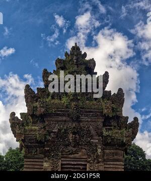 Schnitzereien an einem blauen Himmel mit weißen Wolken, ein Tempelturm in Pengilpuran Modelldorf, Bali, Indonesien Stockfoto